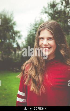 Beautiful natural portrait of teenage girl with long brown hair looking at camera with smile showing teeth Stock Photo