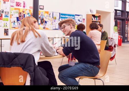 Communal Area Of Busy College Campus With Students Working At Tables Stock Photo