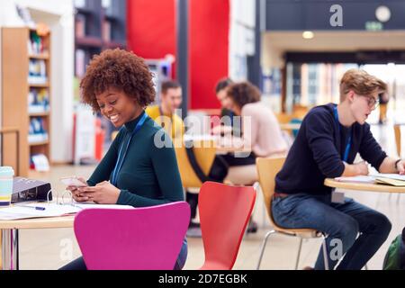 Communal Area Of Busy College Campus With Students Working At Tables Stock Photo