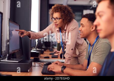 Group Of College Students With Tutor Studying Computer Design Sitting At Monitors In Classroom Stock Photo