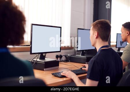 Group Of College Students Studying Computer Design Sitting At Line Of Monitors In Classroom Stock Photo