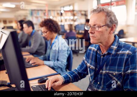 Group Of Mature Adult Students In Class Working At Computers In College Library Stock Photo