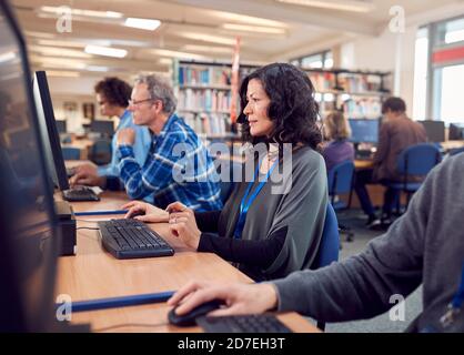 Group Of Mature Adult Students In Class Working At Computers In College Library Stock Photo