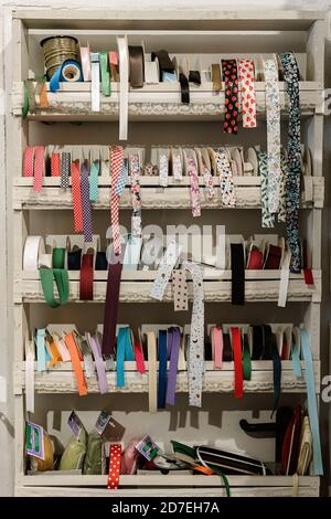 Handmade vintage drawer-shelves with haberdashery accessories and rolls of coloured lace vertically. Decorative ribbons. Haberdashery. Sewing Box Stock Photo