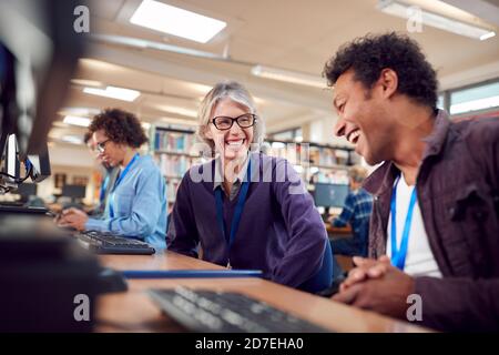 Teacher With Group Of Mature Adult Students In Class Working At Computers In College Library Stock Photo