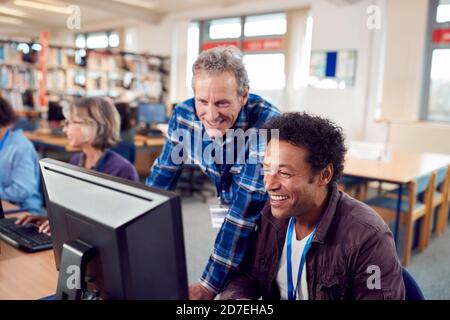 Teacher With Group Of Mature Adult Students In Class Working At Computers In College Library Stock Photo