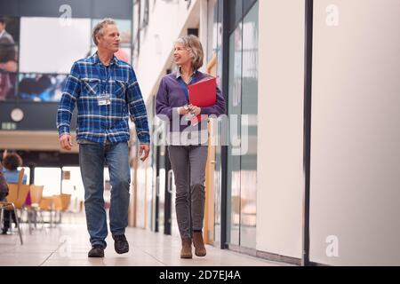 Two teachers are walking and talking together down the school hall ...