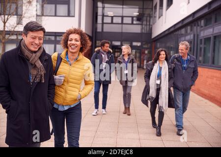 Group Of Smiling Mature Students Walking Outside College Building Stock Photo