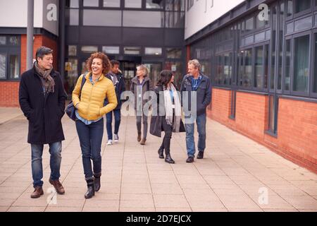 Group Of Smiling Mature Students Walking Outside College Building Stock Photo