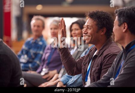 Businessman In Presentation At Conference Raising Hand To Ask Question Stock Photo