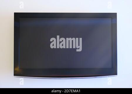 Black big television on white wall, mockup Stock Photo