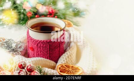 Hot winter tea in a red mug with candied oranges and a warm scarf - rural still life. Stock Photo