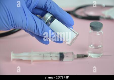 Doctor, nurse or scientist hand in blue nitrile gloves holding flu, measles, coronavirus (COVID-19) vaccine shot for baby and adult vaccination Stock Photo