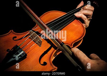 Hands playing a violin on black background cropped closeup Stock Photo