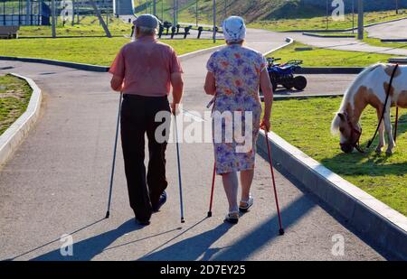 Photo of elderly couple doing nordic walking in the park. Stock Photo