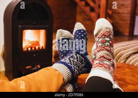 Feet in wool socks warming near fireplace in rustic cabin house. Cozy winter. Stock Photo