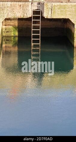 Harbour wall, ladder and reflections Stock Photo