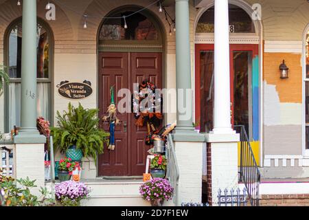 Frederick, MD, USA 10/14/2020: Porch and front door of a vintage house in Frederick Maryland with halloween decorations and potted plants around. This Stock Photo