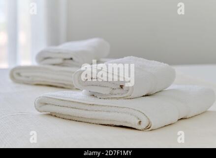 Folded white towels lying on bed in bedroom, close up view Stock Photo