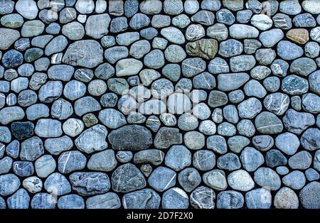 Background from rounded gray stones, pebbles, copy space. Handmade wall surface Stock Photo