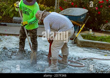 Frederick, MD, USA 10/13/2020: Two construction workers are drilling the concrete floor of a section of Baker Park with a hex breaker hammer. One shov Stock Photo
