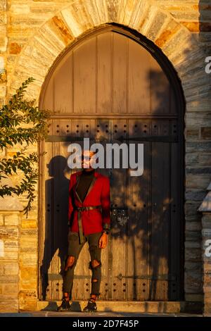 Frederick, MD, USA 10/14/2020:  African American male model wearing fashionable red jacket, sun glasses and ripped jeans poses at a historic place wit Stock Photo