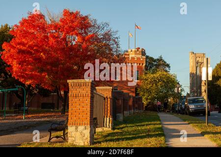 Frederick, MD, USA 10/13/2020: An autumn sunset on the edge of Baker Park featuring historic Frederick Armory with US and Maryland Flags. In backgroun Stock Photo