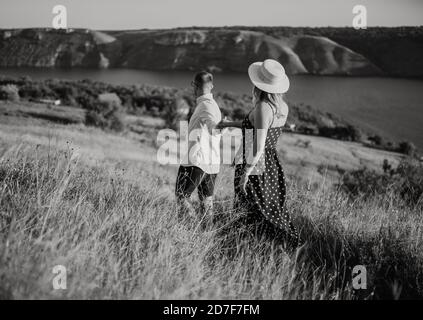 man and woman walking in the meadow at sunset in summer near the lake Stock Photo