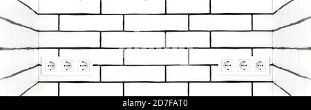 Electrical outlets against a white brick wall. Space for text. Stock Photo