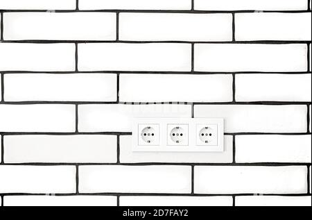Electrical outlets against a white brick wall. Space for text. Stock Photo