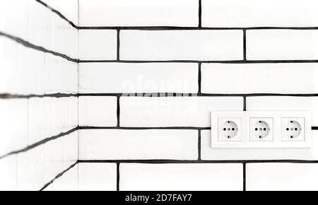 Electrical outlets against a white brick wall. Space for text. Stock Photo