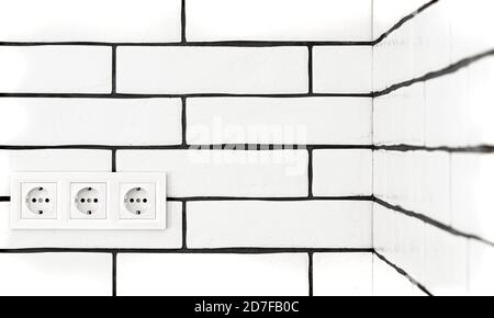 Electrical outlets against a white brick wall. Space for text. Stock Photo