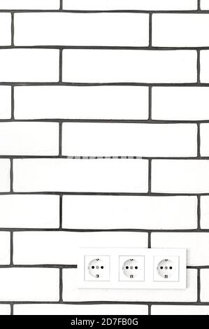 Electrical outlets against a white brick wall. Space for text. Stock Photo