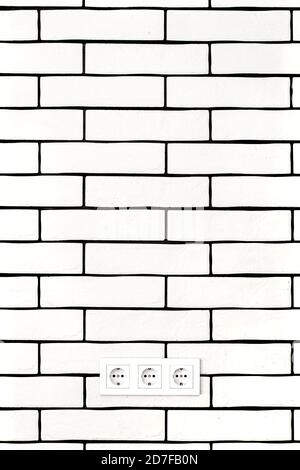 Electrical outlets against a white brick wall. Space for text. Stock Photo
