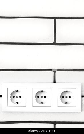 Electrical outlets against a white brick wall. Space for text. Stock Photo