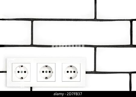 Electrical outlets against a white brick wall. Space for text. Stock Photo