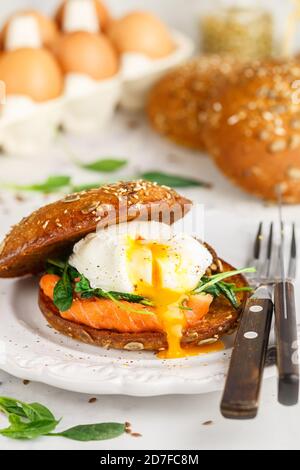 Wholegrain bun with sunflower and flax seeds with salted or smoked salmon (trout), spinach and poached egg. Gourmet sandwich. Delicious breakfast. bru Stock Photo