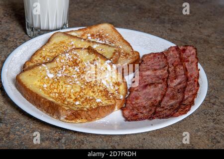 A plate of French toast that has powdered sugar and bacon Stock Photo