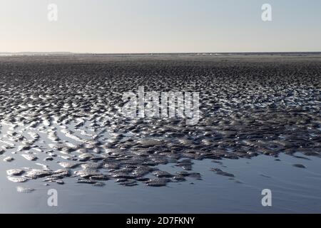 Textures made by water and wind on the sand at the beach, reflections in the water Stock Photo