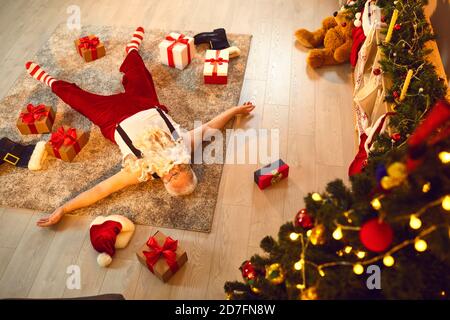 Drunk or simply tired Santa Claus sleeping on floor of a living-room with presents scattered around Stock Photo