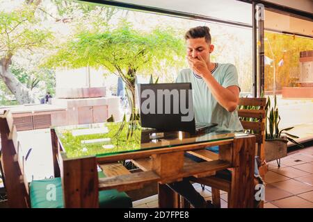 Young Hispanic man yawning while working during the quarantine Stock Photo