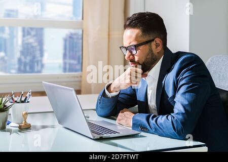 Pondering Thinking Businessman Using Office Computer. Contemplative Man Stock Photo