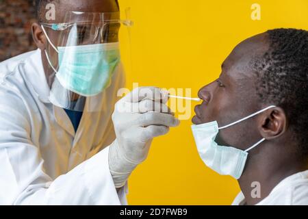 an african medical personnel taking nasal sample for covid-19 testing