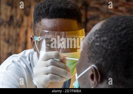 a black medical personnel taking nasal sample for covid-19 testing Stock Photo