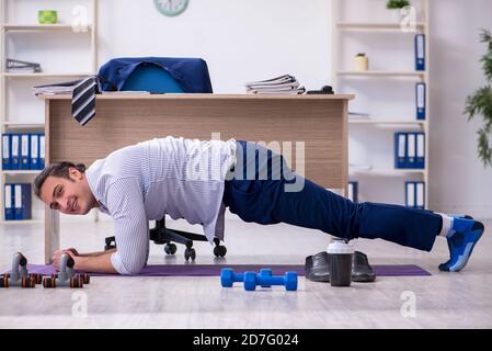 Handsome male employee doing exercises in the office Stock Photo
