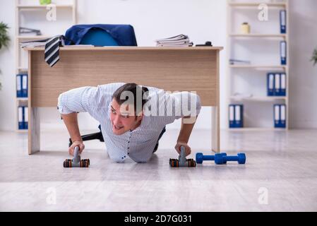 Handsome male employee doing exercises in the office Stock Photo