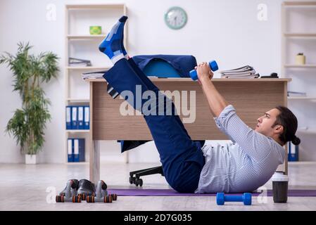 Handsome male employee doing exercises in the office Stock Photo