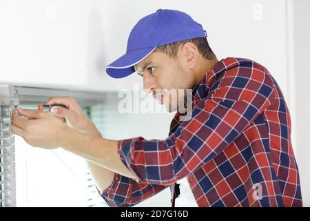 construction worker repairing window in house Stock Photo