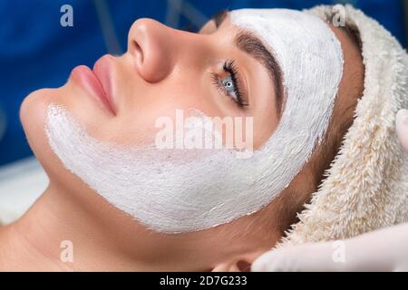 Applying a mask to the face in a beauty salon. Cosmetologist and procedure for rejuvenation and moisturizing. Stock Photo