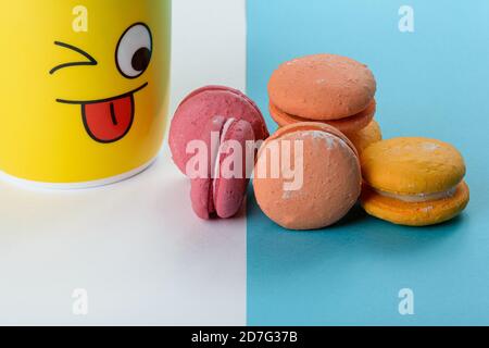 Portion of colorful macaroons being watched by a yellow mug. Stock Photo